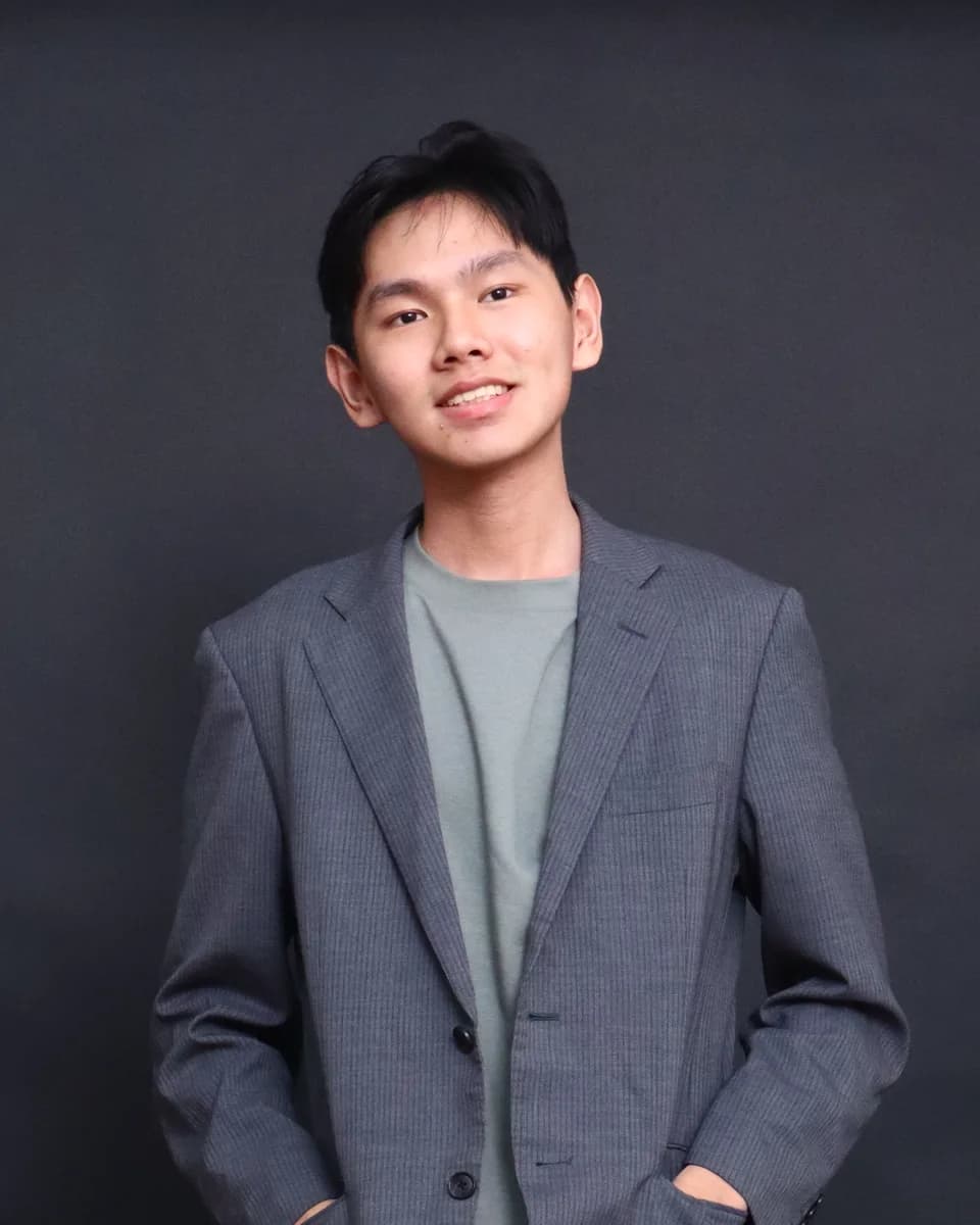 Richard Cen memakai blazer abu-abu, tersenyum